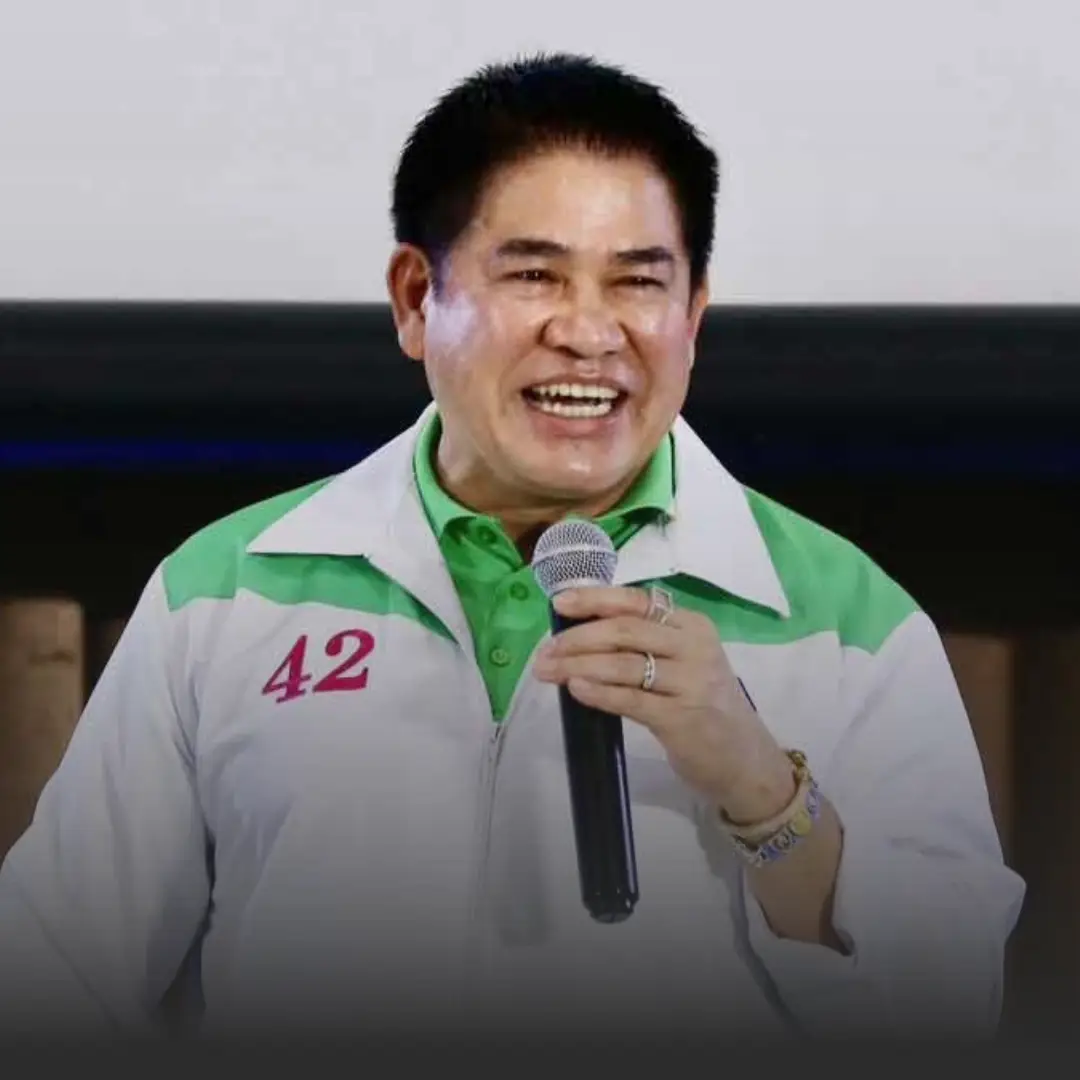 Smiling man in a white and green jacket with the number 42 on the chest, holding a microphone during a talk.