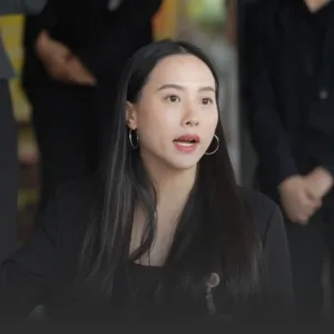 รักชนกเผยยังไม่ชัดไชยชนกเข้าชี้แจง กมธ 18 มิย ปม TH-AI Passport » The Mainstream Woman in a black blazer with hoop earrings speaks during a discussion, blurred people in the background.