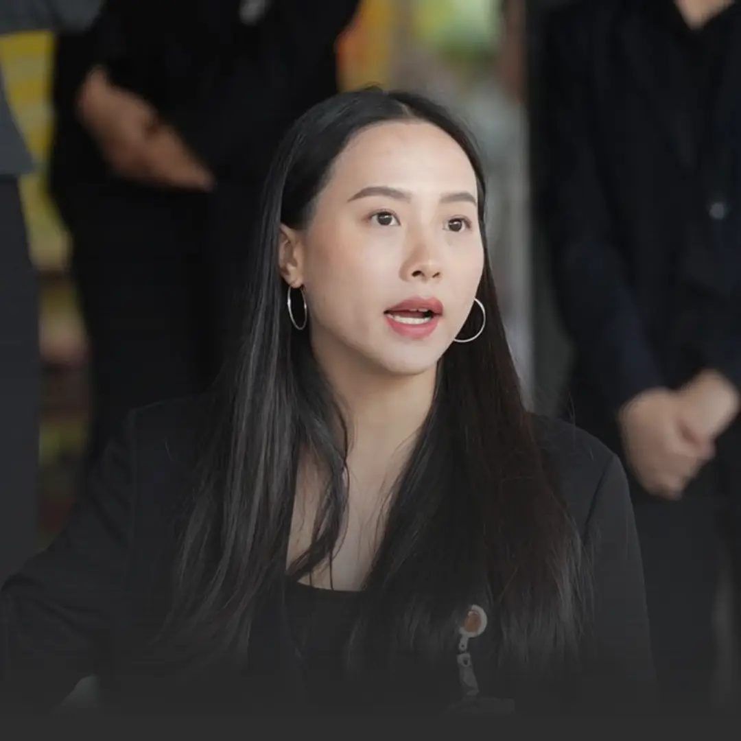 รักชนกเผยยังไม่ชัดไชยชนกเข้าชี้แจง กมธ 18 มิย ปม TH-AI Passport » The Mainstream Woman in a black blazer with hoop earrings speaks during a discussion, blurred people in the background.