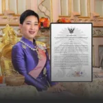 Portrait of a woman in a purple ceremonial outfit and sash, seated beside an ornate framed certificate.