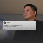 Portrait of a man in a dark suit looking to the right, with a translucent gray speech-bubble style comment containing Thai text and a small profile photo in the corner, set against a blurred background.